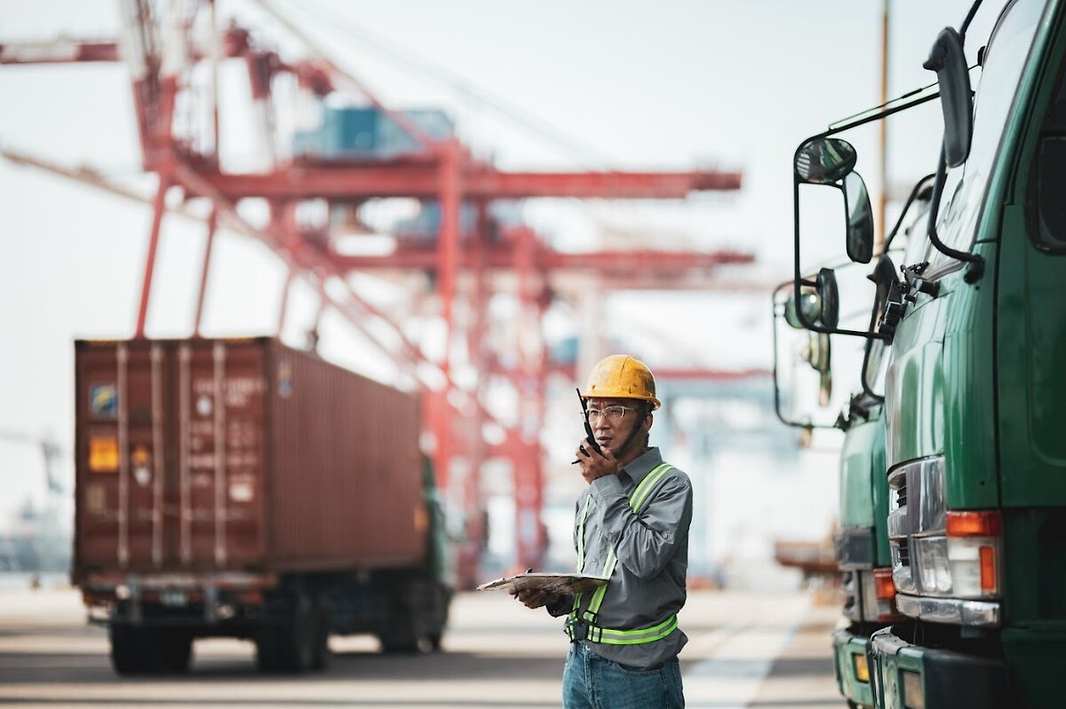 Person directing trucks and containers