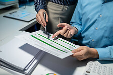 using computer together in office, successful business people working together in a co-working office, two business professionals working on a tech project, business colleagues talking to each other,