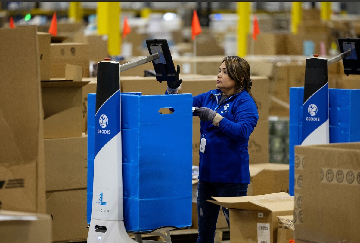 A woman using a Locus Robotics device to pick items at a warehouse