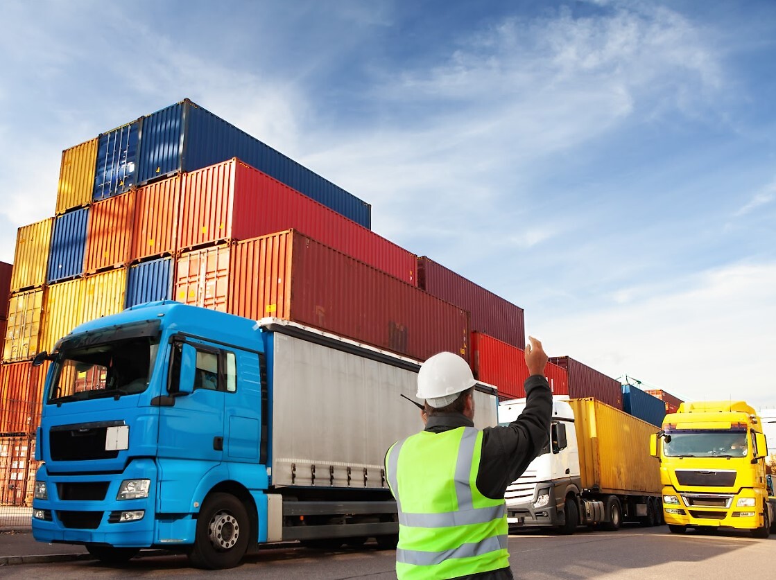 Person directing trucks with containers