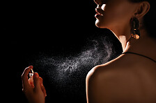 Woman spraying luxury perfume on black background.png